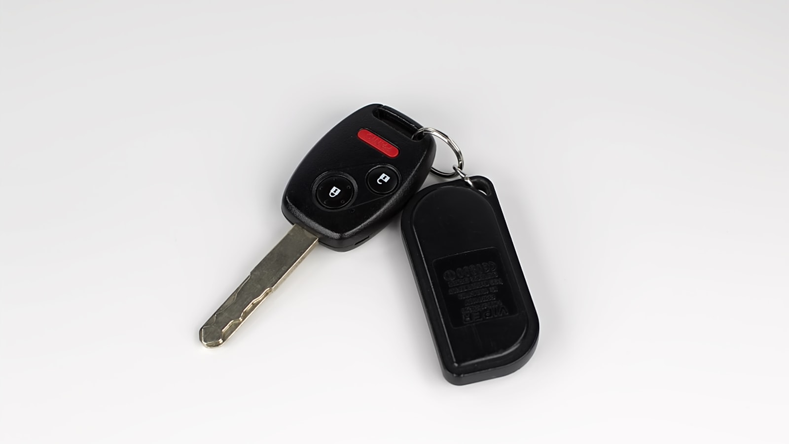 Car key and key fob on a plain background